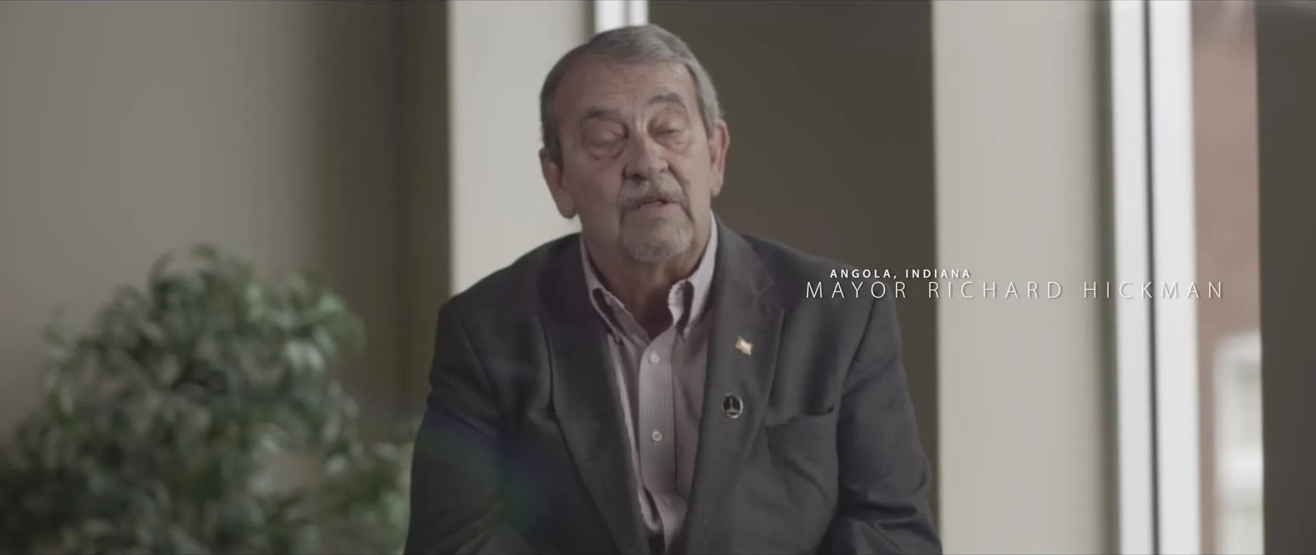 A second mayor interviewed by a window with a lower-third title.