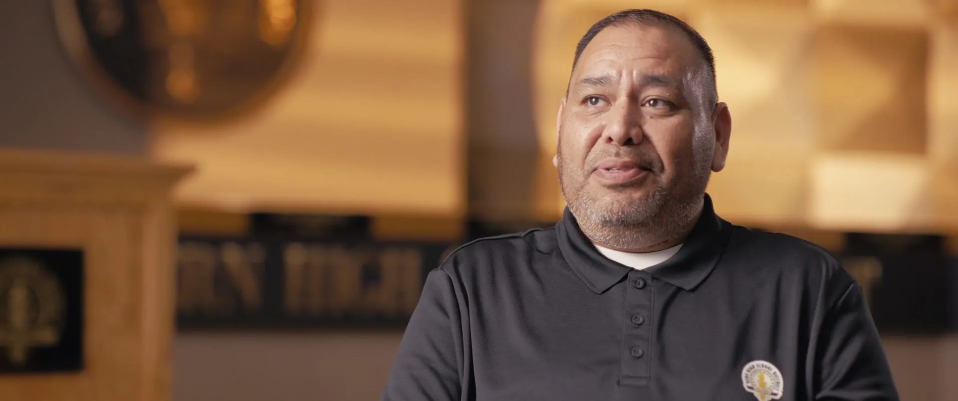 Carlos interviewed in front of a Kern High sign.